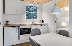 博托比2 Bedroom Nice Apartment In Vggerlse的厨房配有白色橱柜、桌子和床。