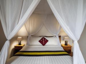 金巴兰Avery Le Nixsun Villas Uluwatu by Waringin Hospitality的一间卧室配有一张带天蓬的白色床