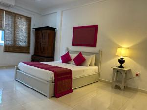 科伦坡City Stay By Sunrise的一间卧室配有带粉红色枕头和台灯的床