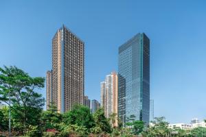 深圳WESU微宿行政公寓(深圳深大地铁店)的一座树木繁茂的城市里两座高耸的摩天大楼