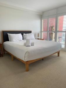 麦夸里港北角公寓酒店的卧室配有一张带白色床单和枕头的大床。