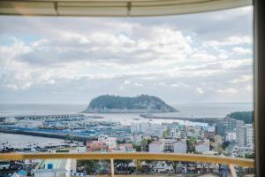 西归浦市Hotel bridge Seogwipo的透过窗户可欣赏到城市和大海的景色