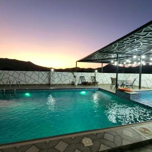 DawwahWadi Bani Khalid - Al Joud Green Hostel的夜间在度假村的游泳池