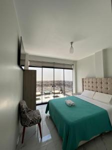 帕拉卡斯Makai - Nayarak Paracas的一间卧室配有一张带绿毯的床和一把椅子