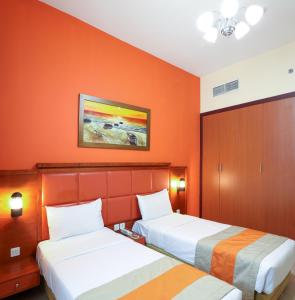 迪拜West Zone Plaza Hotel Apartment (Formerly Winchester Hotel Apts)的橙色墙壁的酒店客房内的两张床