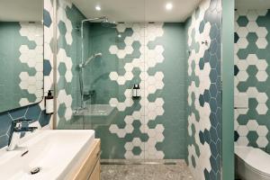 维也纳BASSENA Wien Donaustadt的浴室的墙壁上铺有绿色和白色六角形瓷砖。