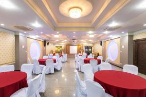 Sangkhaโรงแรมมณีสังขะ的一间会议室,配有红色和白色的桌子和白色的椅子