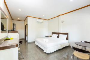 Sangkhaโรงแรมมณีสังขะ的卧室配有白色的床和桌椅