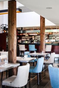 马尔戈Relais de Margaux - Hôtel & Spa的餐厅设有白色的桌子和蓝色的椅子