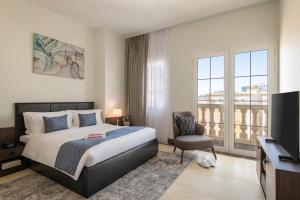 多哈Somerset Al Mansoura Doha的一间卧室配有一张床、一台电视和一把椅子