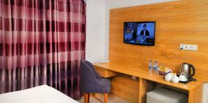 达卡Hotel Afford Inn的一间房间,配有一张桌子和一台墙上的电视