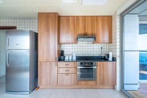 迪拜Veer Apartments - 82nd Floor Princess Tower - Palm View的厨房配有木制橱柜和不锈钢冰箱。