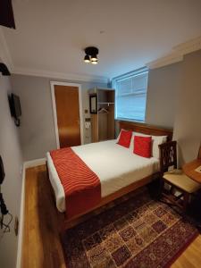 伦敦Aspen Hotel的一间卧室配有一张带红色枕头的大床