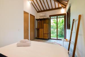 乌布Singgah di Ubud 2的卧室配有白色的床和滑动玻璃门