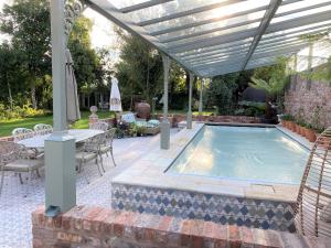 RobyLyndhurst - Victorian villa with heated pool的凉棚下的游泳池,配有桌椅