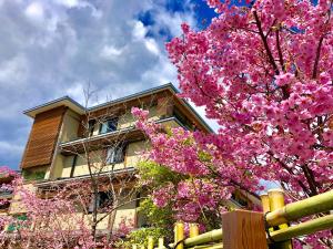 京都Kadensho, Arashiyama Onsen, Kyoto - Kyoritsu Resort的一座建筑物前有粉红色花的树