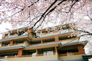 京都Kadensho, Arashiyama Onsen, Kyoto - Kyoritsu Resort的前面有粉红色樱桃树的建筑