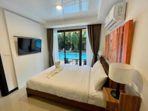 Ban Bo Sai KlangMai Khao Beach Condotel - family condo in 600 meters to beach的一间卧室设有一张床、一台电视和一个游泳池