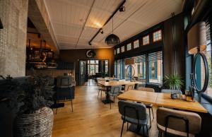 内斯德容餐厅酒店的餐厅设有木桌、椅子和窗户。