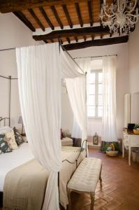 蒙特普齐亚诺Dimora Dell'Erbe Rooms的一间卧室配有一张天蓬床和吊灯。