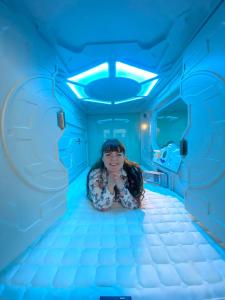 柏林Space Night Capsule Hostel的坐在蓝色灯室里的女人