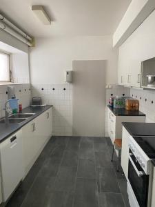纳尔维克Sjømannskirken Narvik的厨房配有白色橱柜和瓷砖地板。