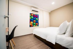 吉隆坡Chill Suites Kuala Lumpur的卧室配有一张床,墙上挂有绘画作品