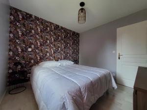丰特奈勒孔特Hortensia, Gîte famille et amis的一间卧室配有一张带花卉壁纸的大床