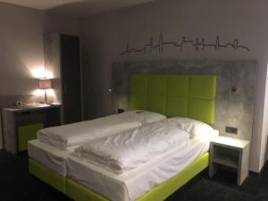 多瑙河畔迪林根SleepySleepy Hotel Dillingen的一间卧室配有一张带绿色床头板的床
