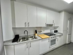 里贝拉Apartamento en palmeira - Colores del Barbanza Naranja的厨房配有白色橱柜、水槽和微波炉