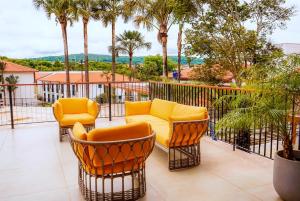 皮雷诺波利斯Quinta Santa Bárbara ECORESORT的阳台配有椅子、沙发和棕榈树