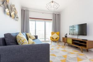波尔蒂芒Solemar - 2Pools - WIFI 500MBps - AC - Portimão的客厅配有蓝色的沙发和电视