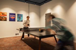 泰比HomeX Hotel for Gamers的两个人在带桌子的房间打乒乓球