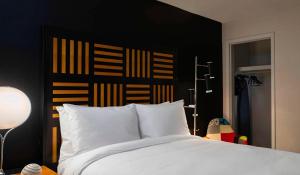德梅因德梅因萨弗里万丽酒店的一间卧室配有一张白色的床和黑色床头板