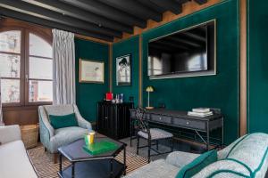 塞维利亚Hotel Casa Palacio Don Ramón的客厅设有绿色墙壁和电视。