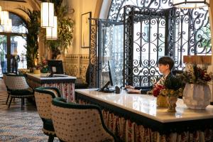 塞维利亚Hotel Casa Palacio Don Ramón的坐在酒店大堂办公桌旁的男人