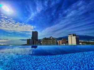 芽庄Grand Tourane Nha Trang Hotel的一座大型游泳池,其背景是城市天际线