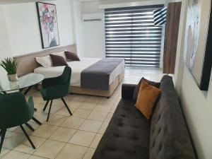 拉纳卡Larnaca Bay Suites的一间卧室配有一张床、一张沙发和一张桌子