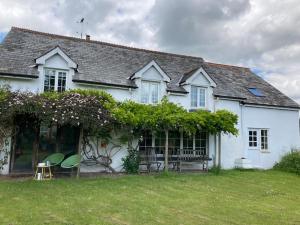 埃克塞特Rural Devon retreat in stunning Exe Valley.的院子里的白色房子,配有长凳和椅子