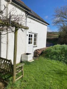 埃克塞特Rural Devon retreat in stunning Exe Valley.的前面有长凳的白色房子