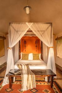 Aitong费尔蒙马拉野生动物俱乐部酒店的一间卧室配有一张带木凳的天蓬床