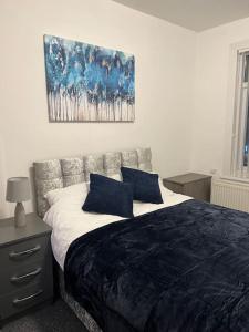 沃特福德Spacious 3 bed flat near Watford Junction的一间卧室配有一张带两个蓝色枕头的床