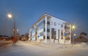罗瓦涅米First Aparthotel Dasher的白房子在晚上在白雪 ⁇ 的街道上