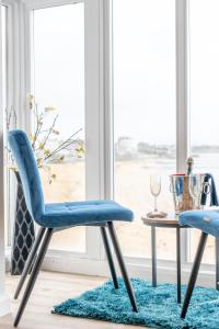 马盖特The Pearl Suite by Margate Suites的两把蓝色的椅子和一张桌子,放在窗户前