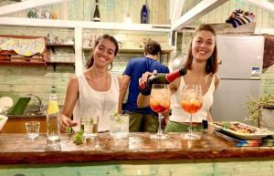 波利齐杰内罗萨HAPPY GLAMPING MADONIE的两个女人站在柜台上把酒倒进眼镜