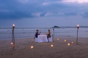 韦利格默Weligama Bay Marriott Resort & Spa的两人坐在海滩上的桌子上