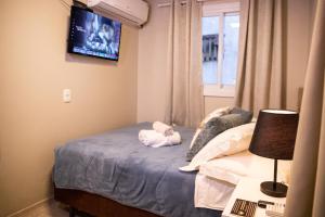 格拉玛多Hospedagem Vila Suiça Centro的卧室配有一张床,墙上配有电视。