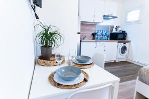 布雷斯地区布尔格SPACIEUX - Proche-gare - Parking的白色的厨房,配有带盘子和酒杯的桌子