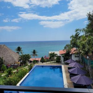 拉利伯塔德Kayu Surf Resort的享有带遮阳伞的游泳池和大海的景致。