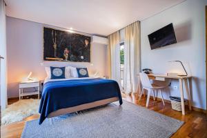 塞辛布拉7 bedrooms villa with private pool enclosed garden and wifi at Sesimbra的一间卧室配有蓝色的床、一张桌子和一张书桌